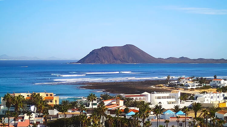 Panoramic view from Corralejo El Campanario tower, capturing Rocky Point surf spot, the sandy dunes of Corralejo Natural Park, and the distant Los Lobos Island.