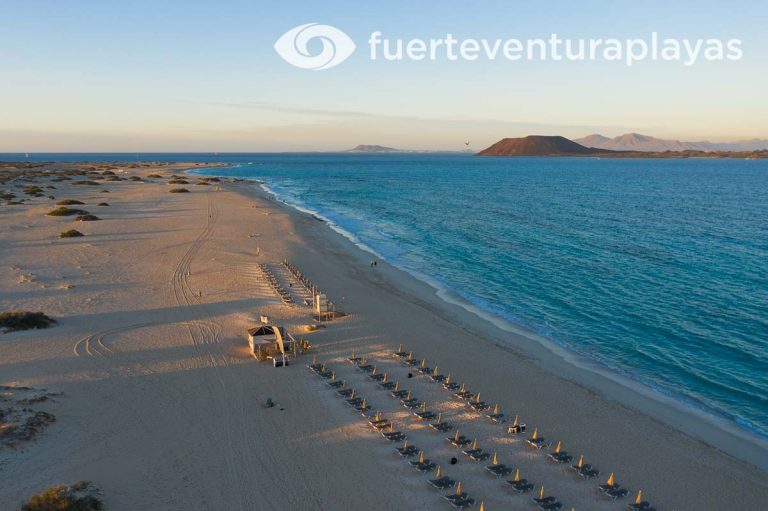 Vista panorámica de la playa de La Entubadera, en Fuerteventura, con sus extensas arenas blancas y sus aguas turquesas.