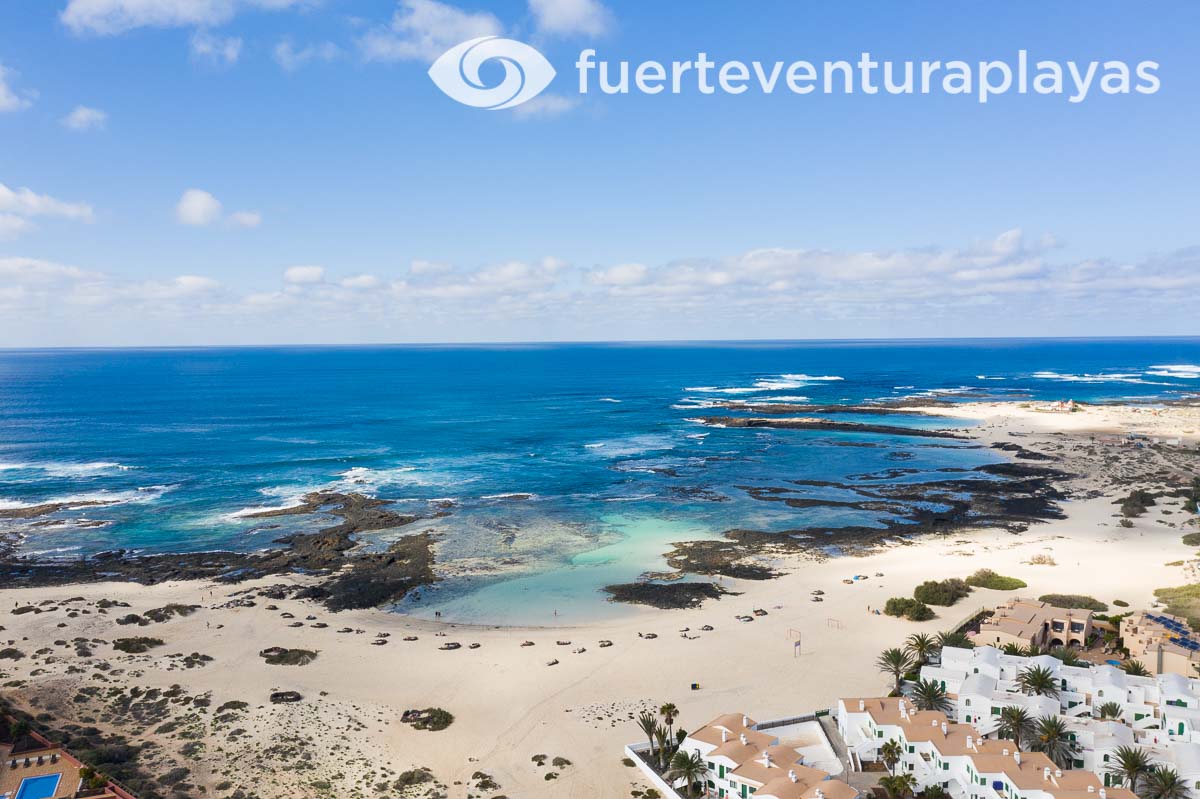 Playa Marfolín in El Cotillo: a spacious urban beach with pristine white sands, turquoise waters, and a protective coral reef.